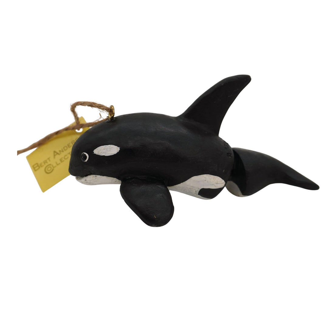 Black and white orca whale toy with a gold tag on a white background