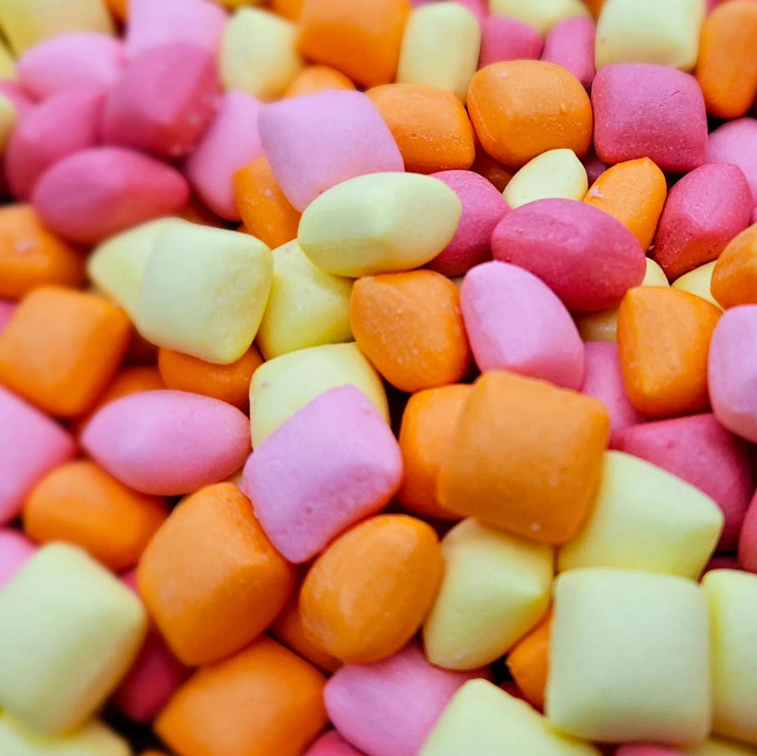 A close-up pile of small, pastel-colored candy pieces in pink, orange, and pale yellow.