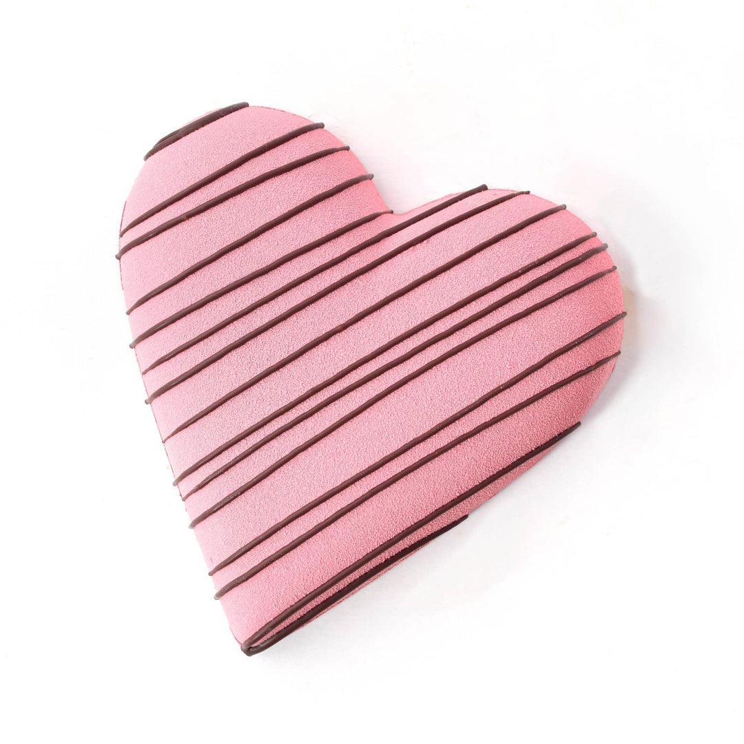 Heart-shaped pink cookie with chocolate drizzle on a white background
