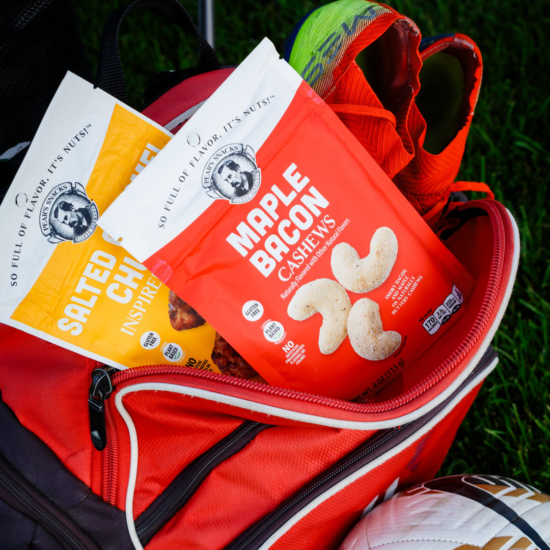 Red cooler bag with snacks and a soccer ball on grass