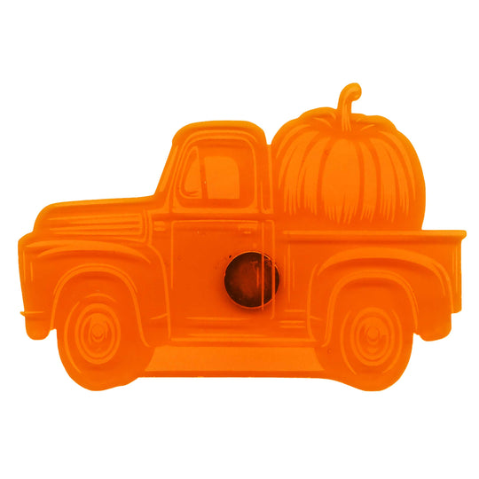 An orange plastic decorative item shaped like a vintage pickup truck carrying a large pumpkin, shown on a plain white background.
