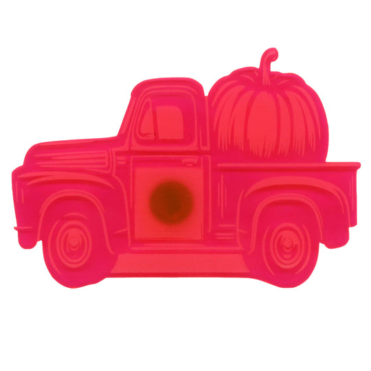A bright pink plastic cookie cutter shaped like a vintage pickup truck carrying a large pumpkin, shown on a plain white background.