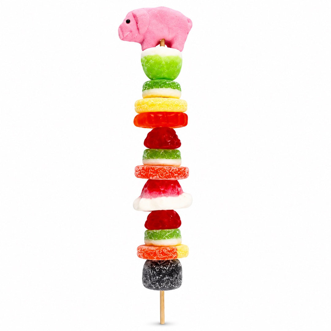 Pig candy kabob featuring a pink pig candy topper and assorted fruit-flavored candies on a wooden skewer, isolated on a white background.