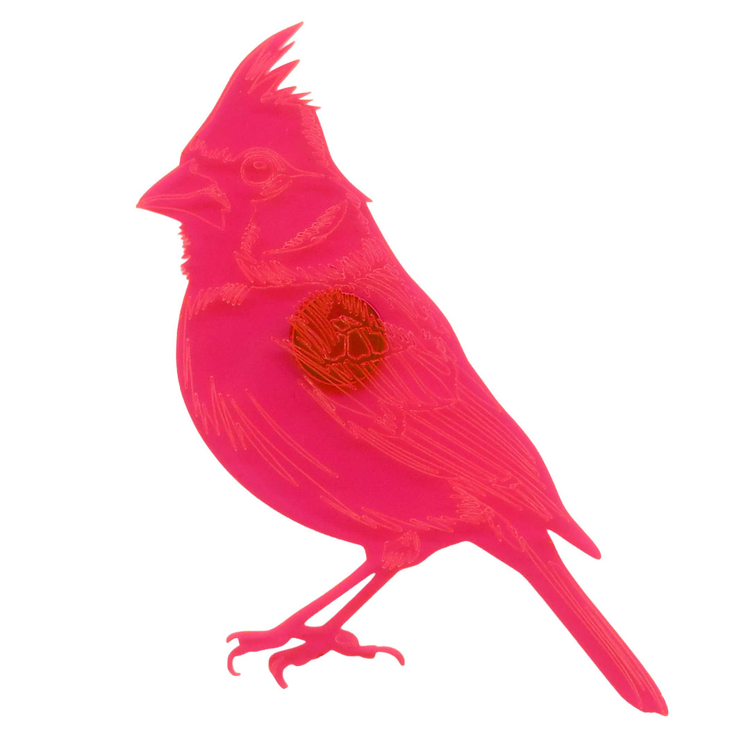 A bright pink bird-shaped decorative object with engraved linework and a circular orange emblem on its chest, shown on a plain white background.