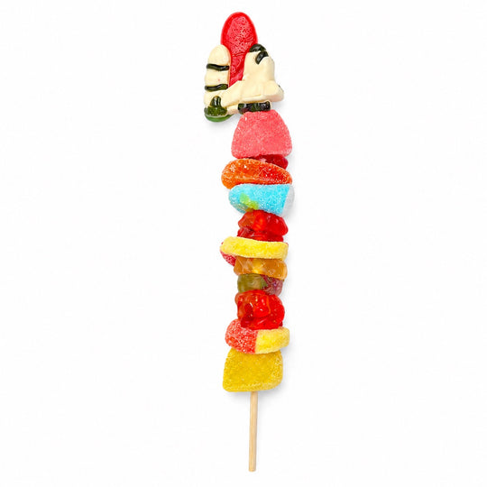 Rocket candy kabob topped with a red and white rocket gummy and stacked with assorted gummy candies on a wooden skewer, isolated on a white background.
