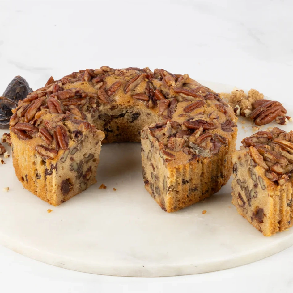 Pecan cake with a slice removed on a marble board
