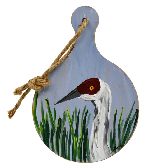 Decorative hanging sign with a painted crane and grass design on a white background