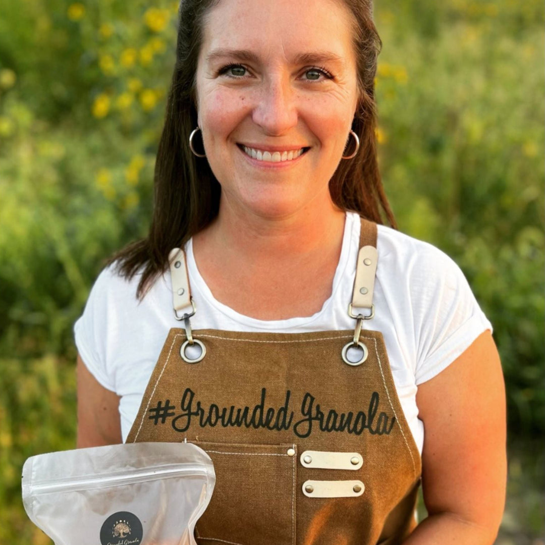 Woman holding a bag of #GroundedGranola in a natural setting