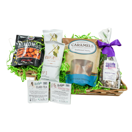 Gourmet gift basket with various treats including caramels, nuts, and teas on a white background.