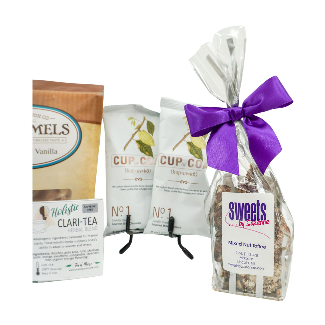 Assorted food products including a box of tea, bags of coffee, and a bag of mixed nut toffee with a purple bow on a white background.