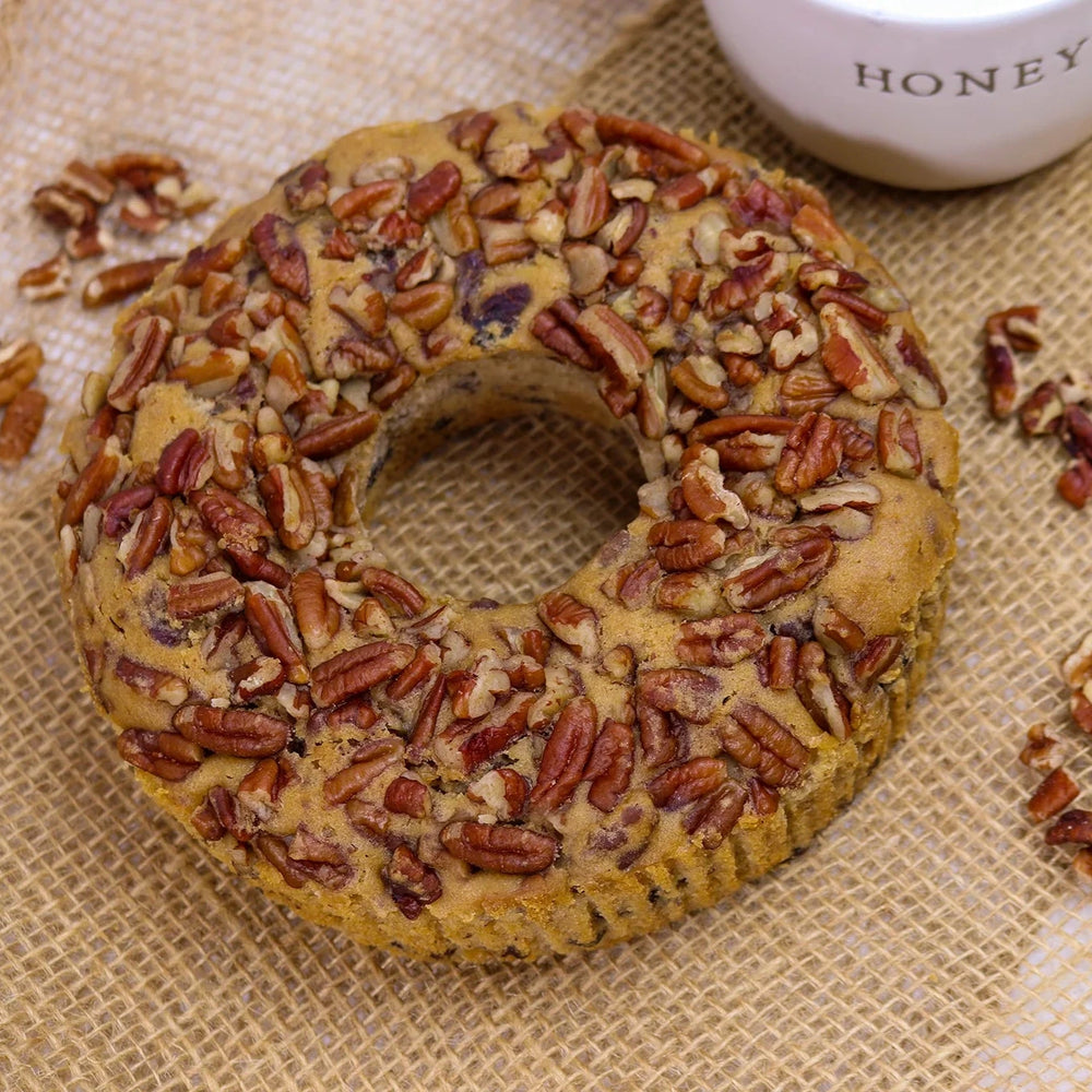 Pecan Cake with pecans on a textured surface with a container labeled 'Honey'.