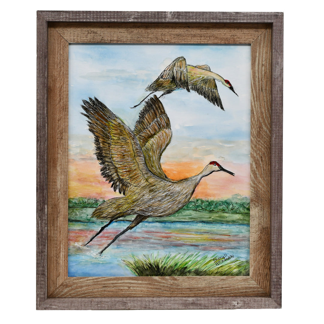 Framed artwork of two cranes flying over a landscape with a wooden frame.