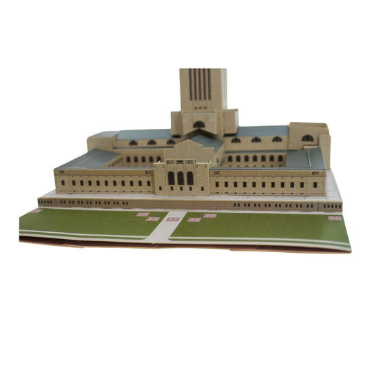 Model of a large building with a green lawn in front on a white background