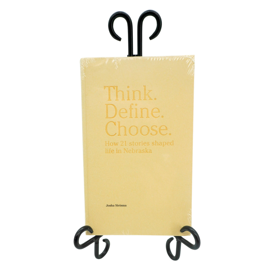 Book titled 'Think. Define. Choose.' on a black stand with a white background