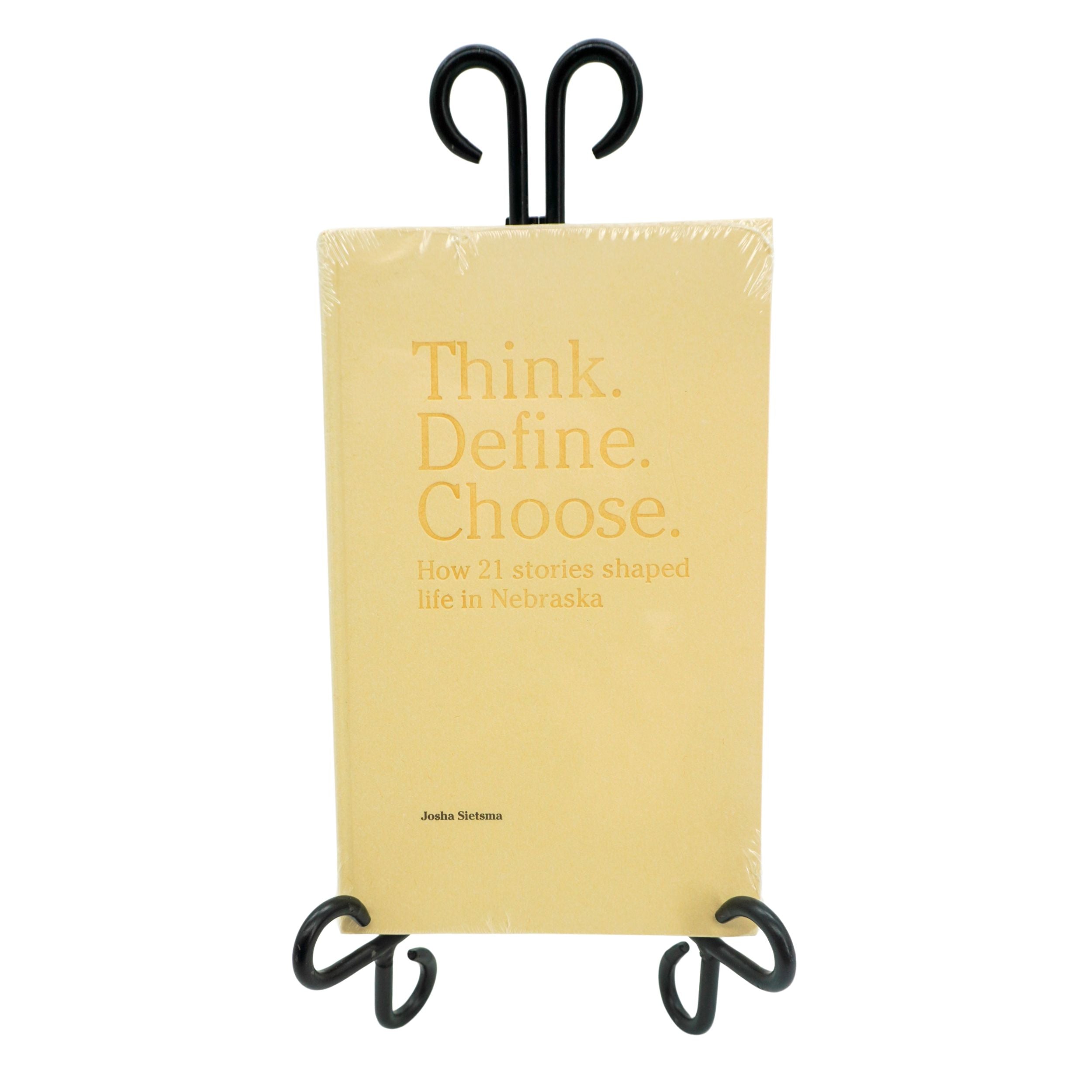Book titled 'Think. Define. Choose.' on a black stand with a white background