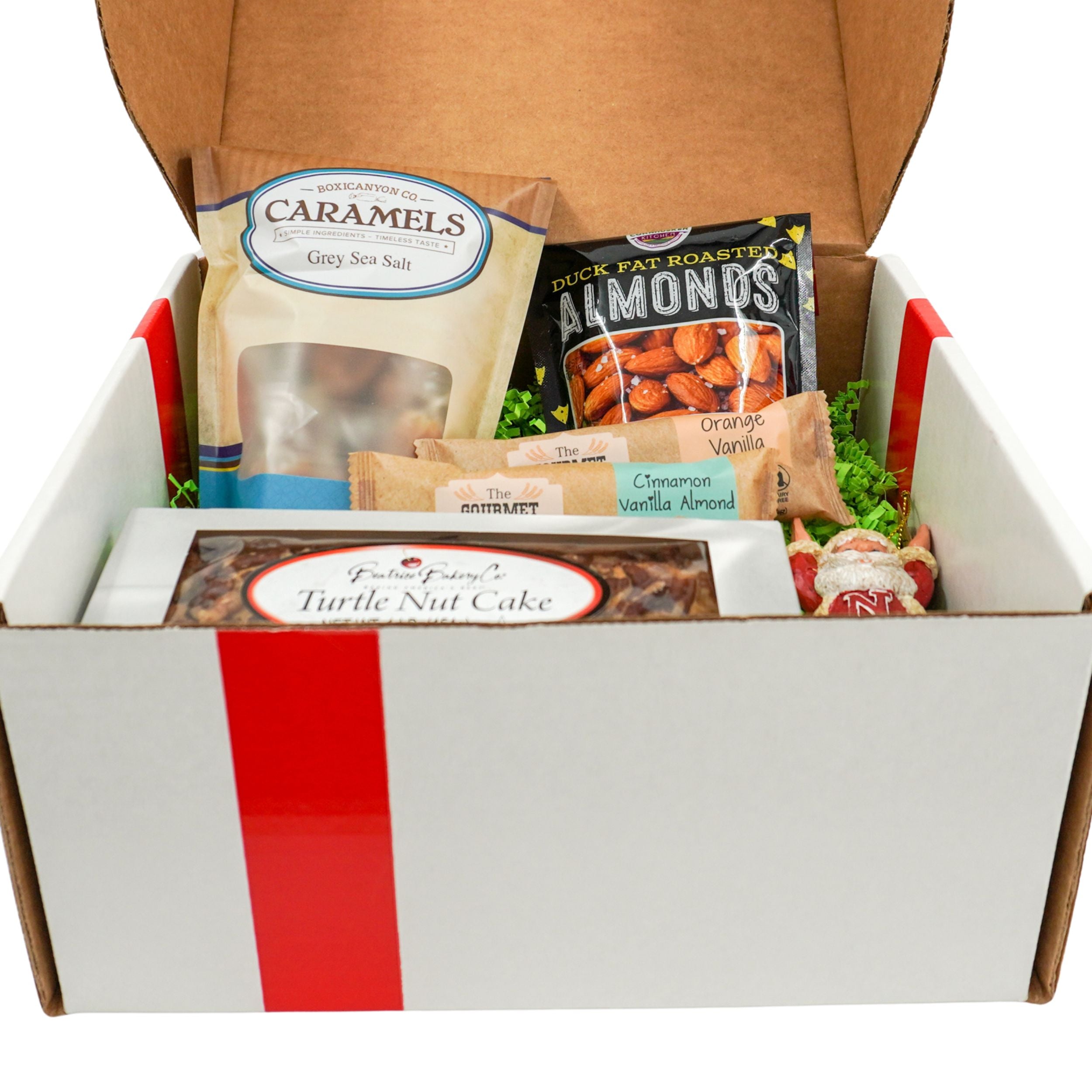 Gift box with assorted treats including caramels, almonds, and a turtle nut cake.