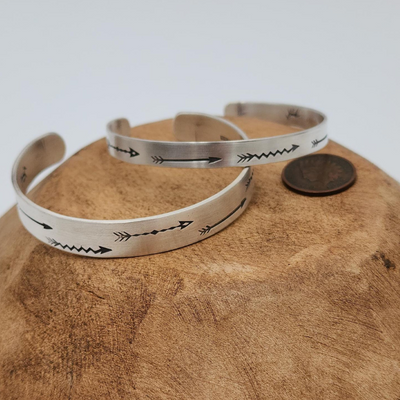 2 Hand Stamped Arrow Design Sterling Silver Bracelet on Wood with Coin for Comparison