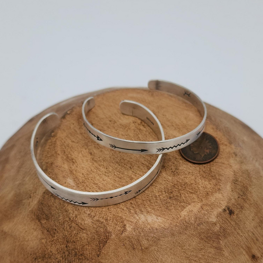 2 Hand Stamped Arrow Design Sterling Silver Bracelet on Wood with Coin for Comparison