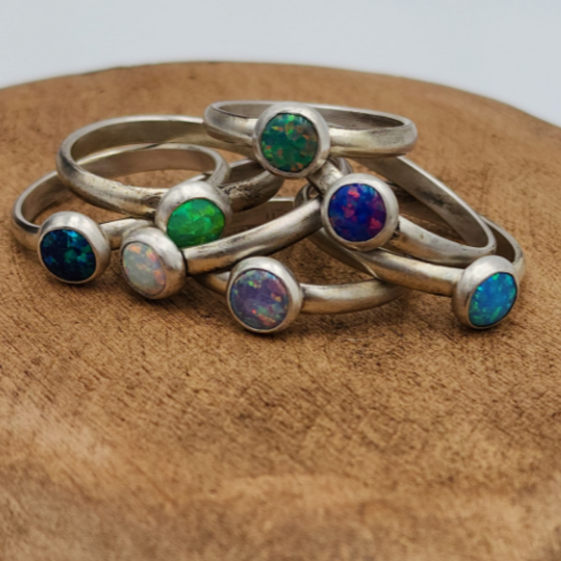  Multiple Sterling Silver Colored Opal Rings Stacked in Pile on Wood