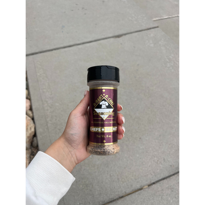 A Hand Holding A Bottle Of A-Rent-A-Chef Chef's Secret All Purpose Seasoning 