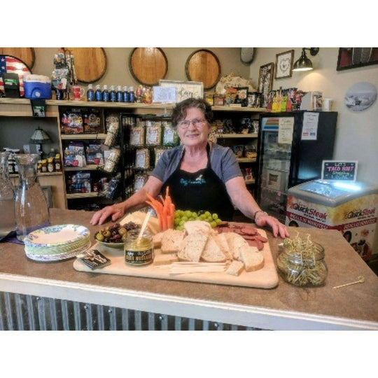 Betty, CEO of Buzz Savories standing and sampling next to her product.