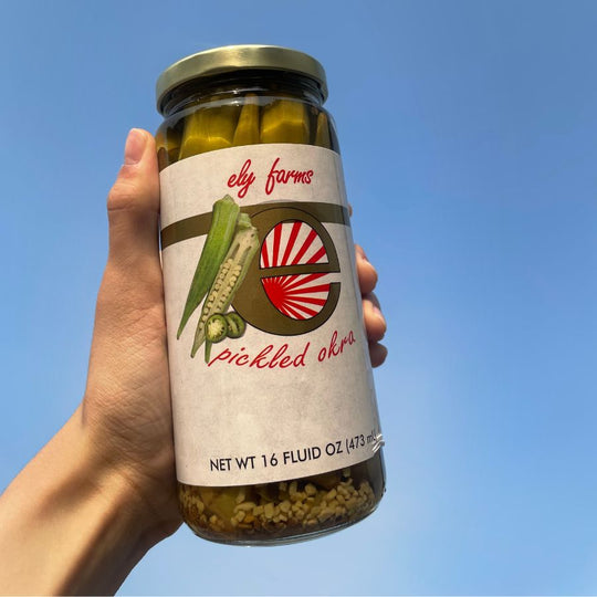 A jar of pickled okra held up to the sky.