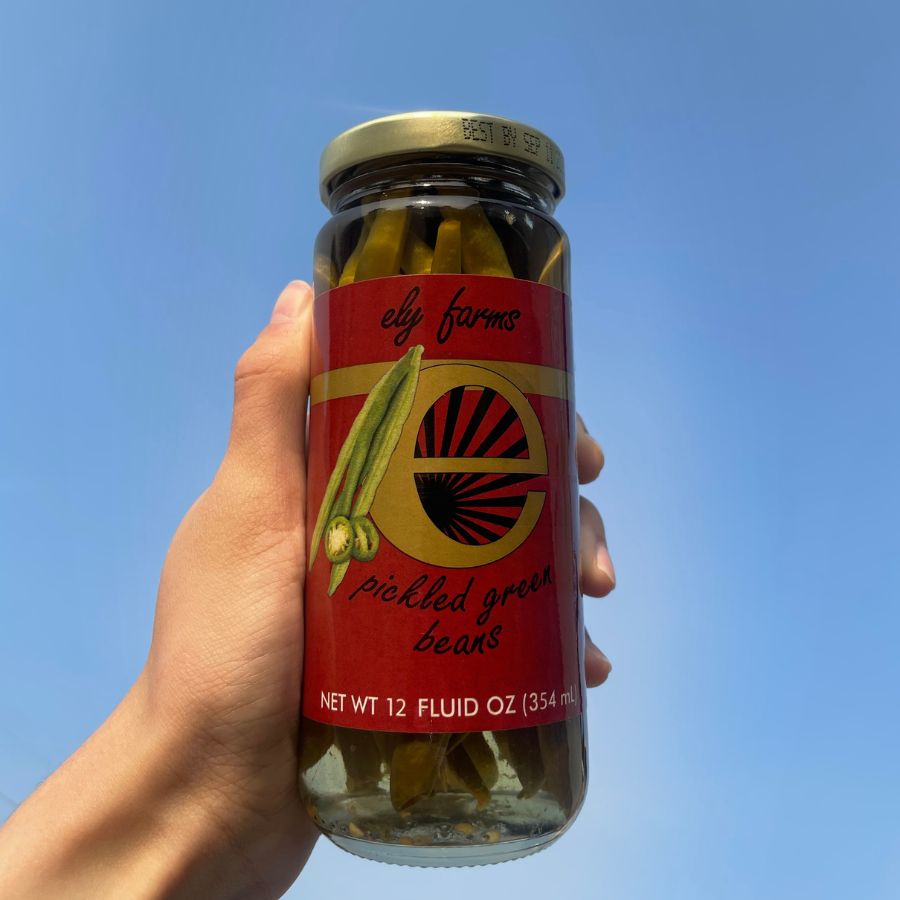 A jar of pickled green beans getting held up to the sky