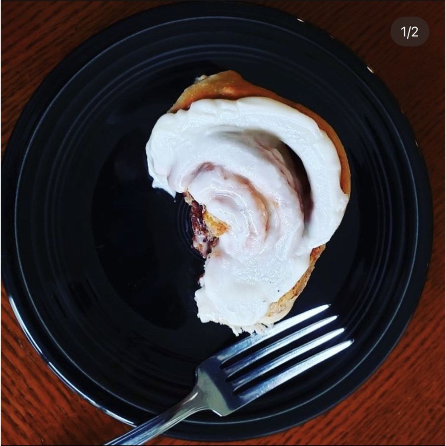 One Frosted Cinnamon Roll On A Plate With A Fork