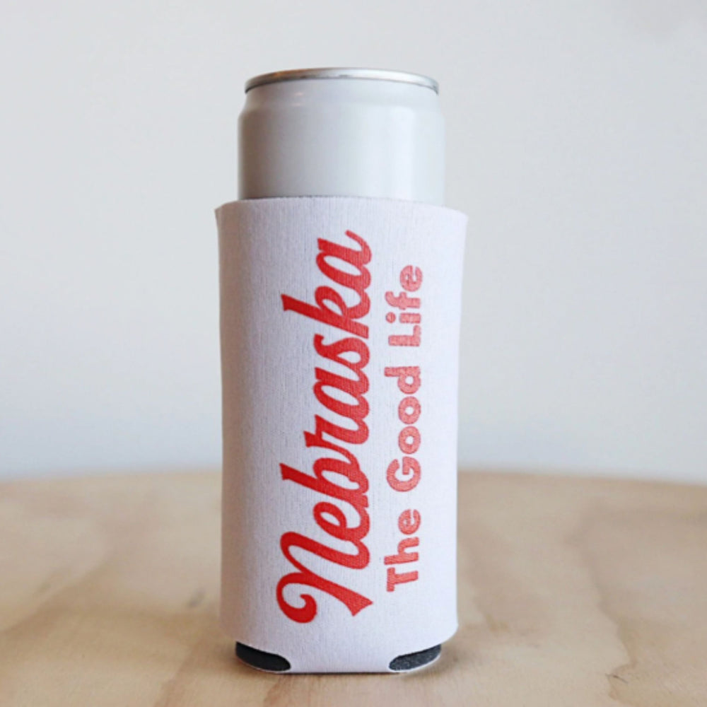 A white koozie with red text 'Nebraska The Good Life' printed on it, designed to hold a beverage can.