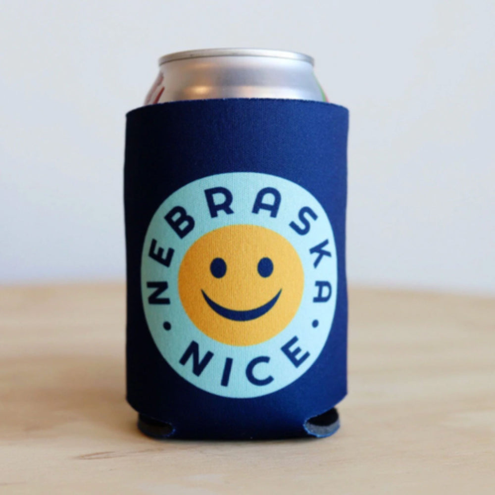 A blue koozie with a smiley face and the text 'NEBRASKA NICE' printed on it, designed to hold a 12 oz can.