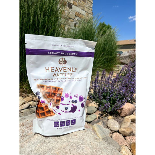 One 13.5 oz. Bag of Blueberry Heavenly Waffles Mix Outside On A Rock With A Floral Background