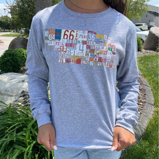 Girl wearing long sleeve gray nebraska license plate shirt.