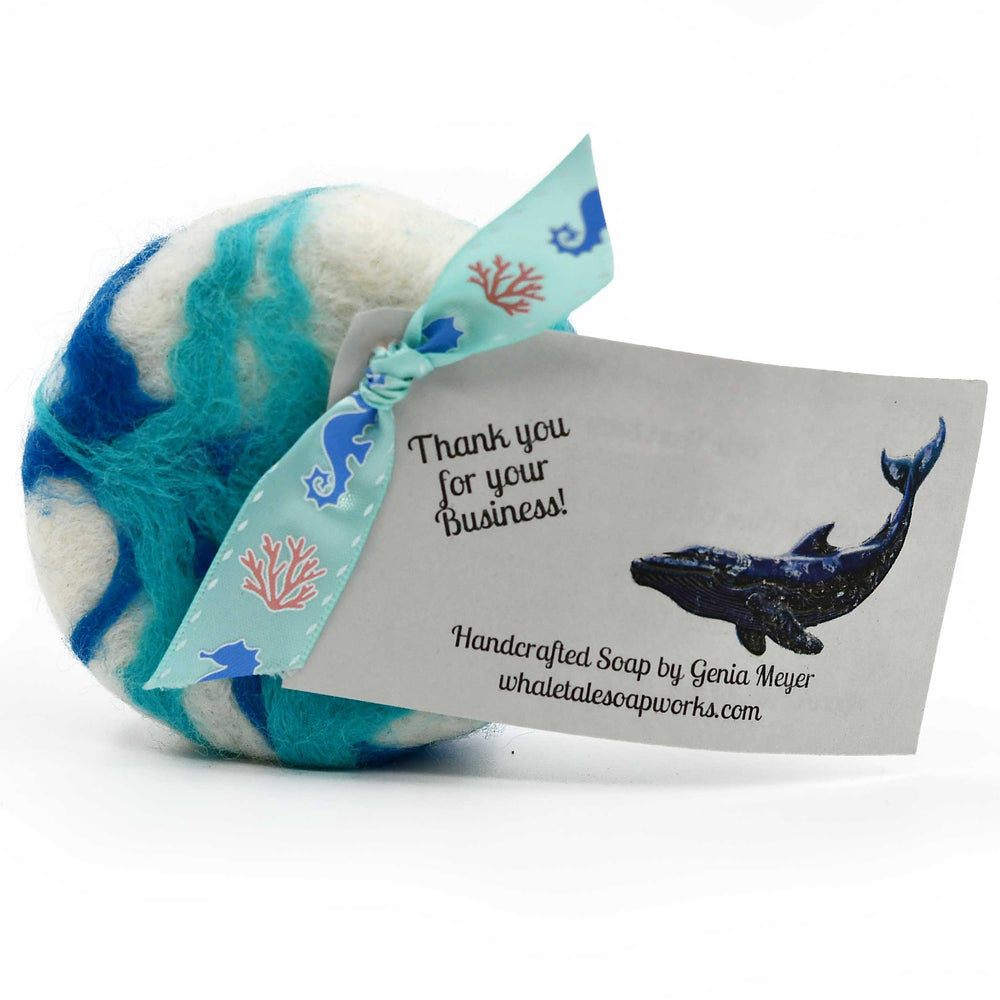 Handcrafted soap with a whale design and a business card on a white background