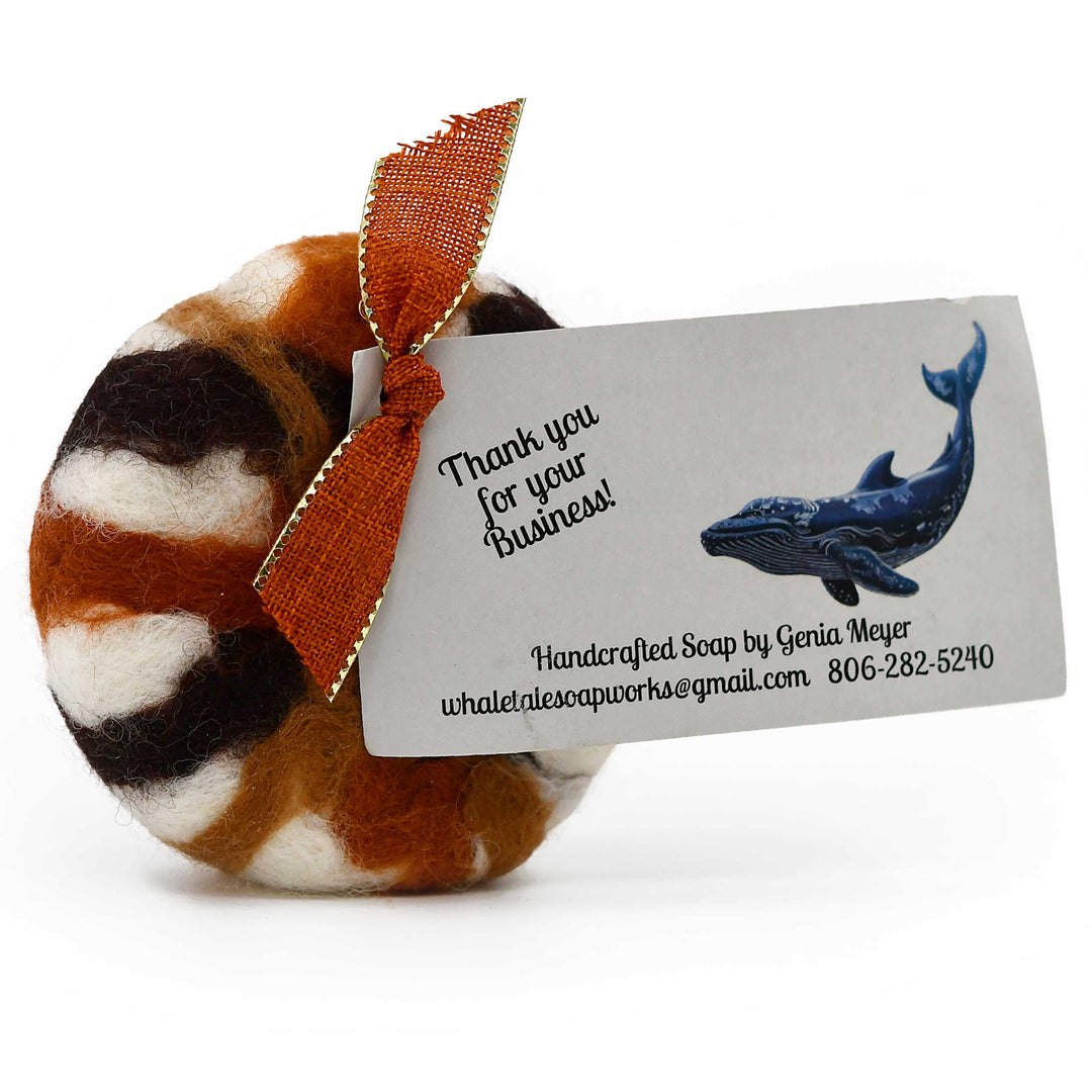 Handcrafted soap with a decorative bow and business card on a white background