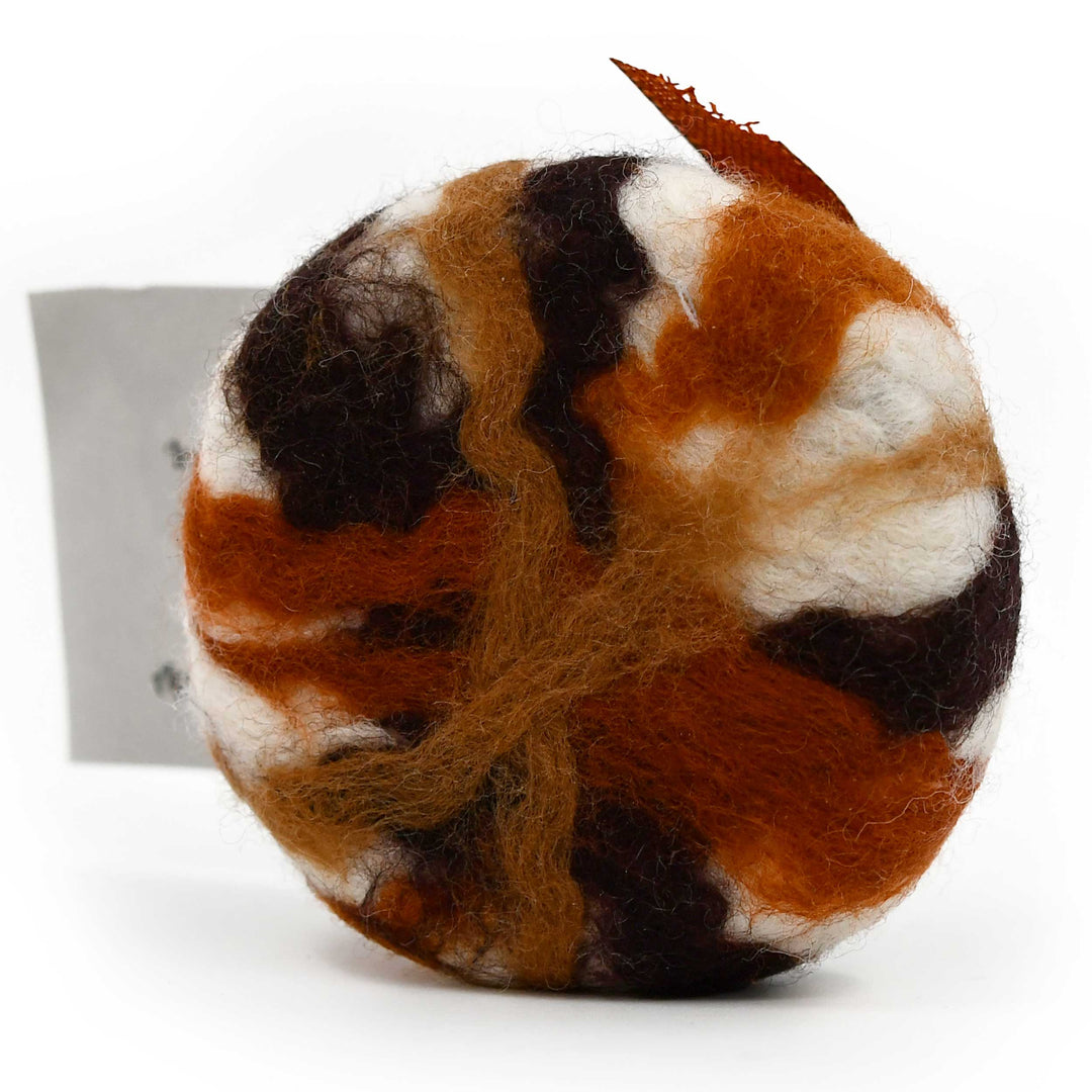 Round felted soap with brown, black, and white pattern on a white background