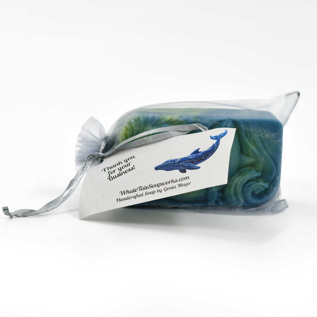 Whale-themed soap in a clear packaging with a business card on a white background