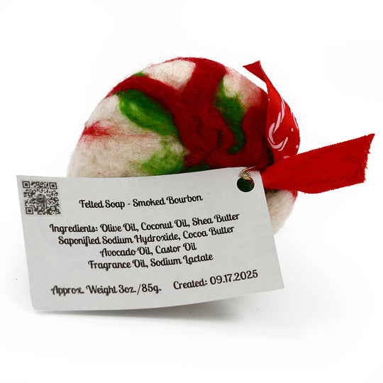 Felted soap with a red and green pattern on a white background, featuring a label with text.