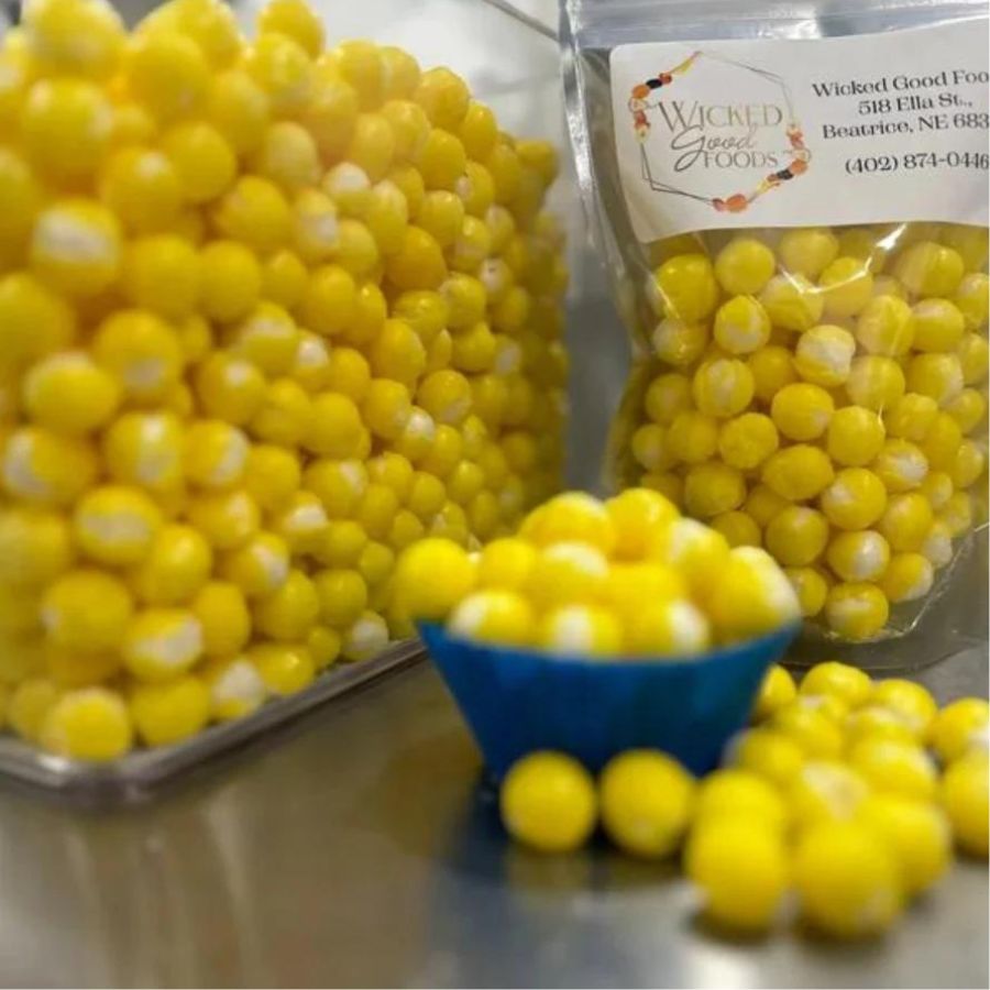 A pile, bag, and bin of freeze dried lemon head bites on a silver countertop