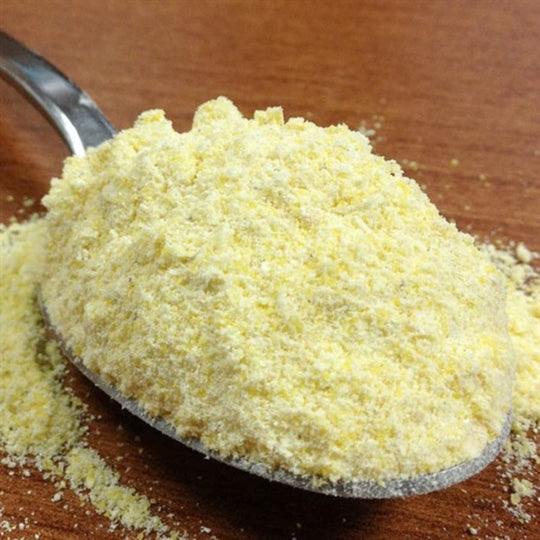 Spoonful Of Organic Yellow Cornmeal Resting On A Brown Wooden Table