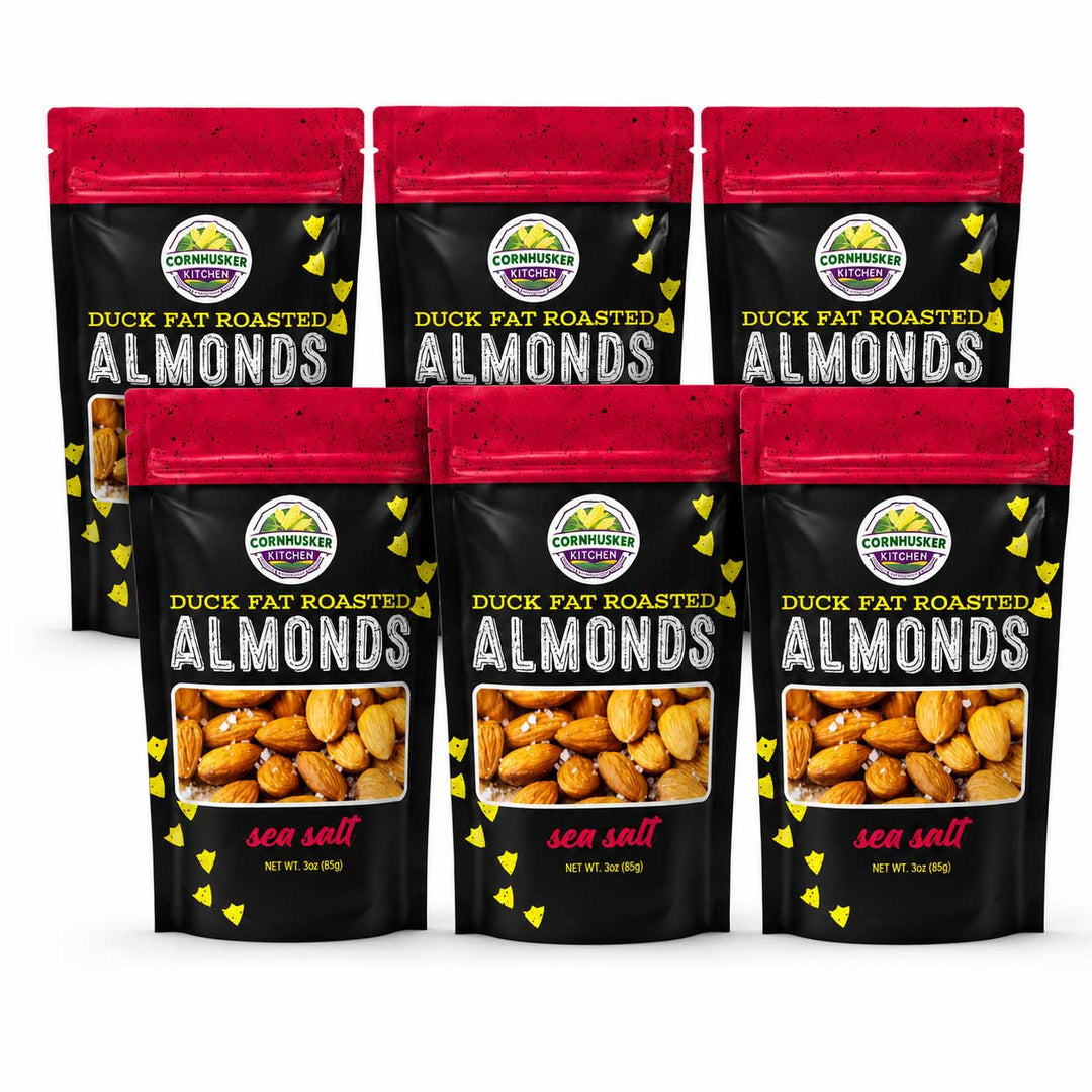 Six stand-up pouches of Cornhusker Kitchen Duck Fat Roasted Almonds (sea salt flavor) arranged in two rows of three on a white background.
