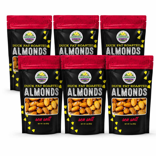 Six stand-up pouches of Cornhusker Kitchen Duck Fat Roasted Almonds (sea salt flavor) arranged in two rows of three on a white background.