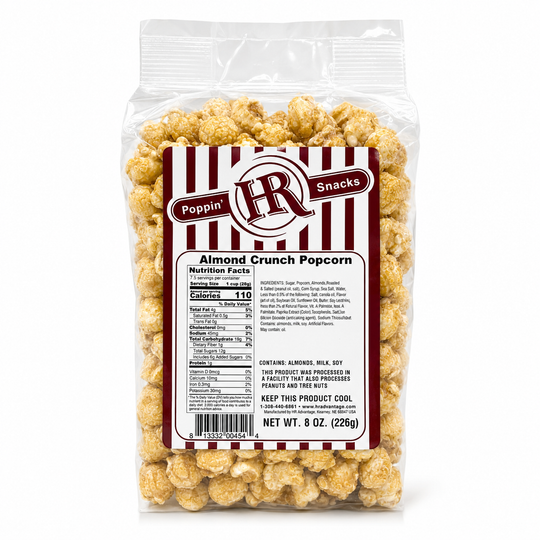 A 8 oz clear plastic bag of Poppin' HN Snacks Almond Crunch Popcorn, showing the back of the package with nutrition facts and product details, filled with golden-brown coated popcorn on a white background.