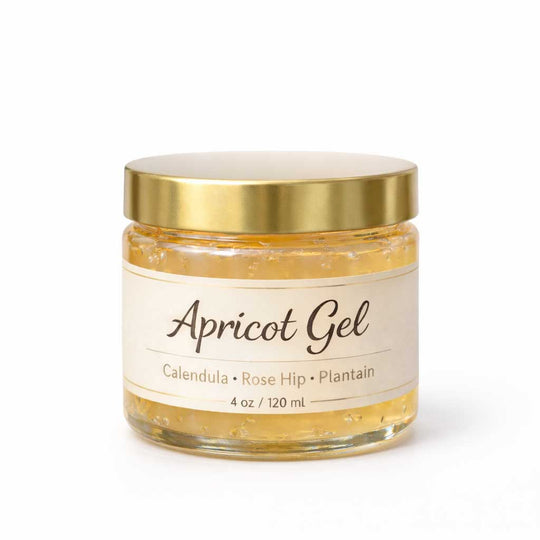 Jar of apricot gel with a gold lid on a white background