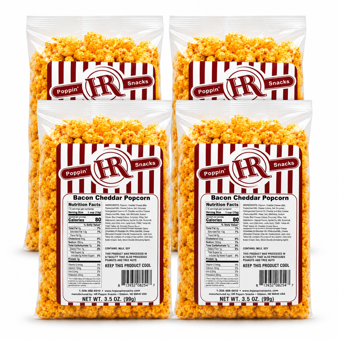 Four bags of Poppin' IR Bacon Cheddar Popcorn arranged in a 2x2 grid on a white background. The clear bags show the golden-yellow popcorn inside and feature red-and-white striped labels with the Poppin' IR logo and product details.