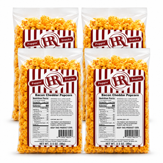 Four bags of Poppin' IR Bacon Cheddar Popcorn arranged in a 2x2 grid on a white background. The clear bags show the golden-yellow popcorn inside and feature red-and-white striped labels with the Poppin' IR logo and product details.