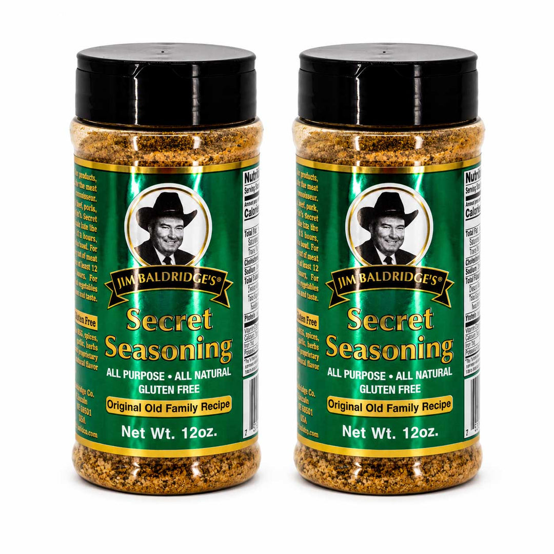 Two jars of Jim Baldridge's Secret Seasoning displayed side-by-side on a white background. The seasoning bottles feature green labels with a portrait of Jim Baldridge, gold lettering, and a black cap.