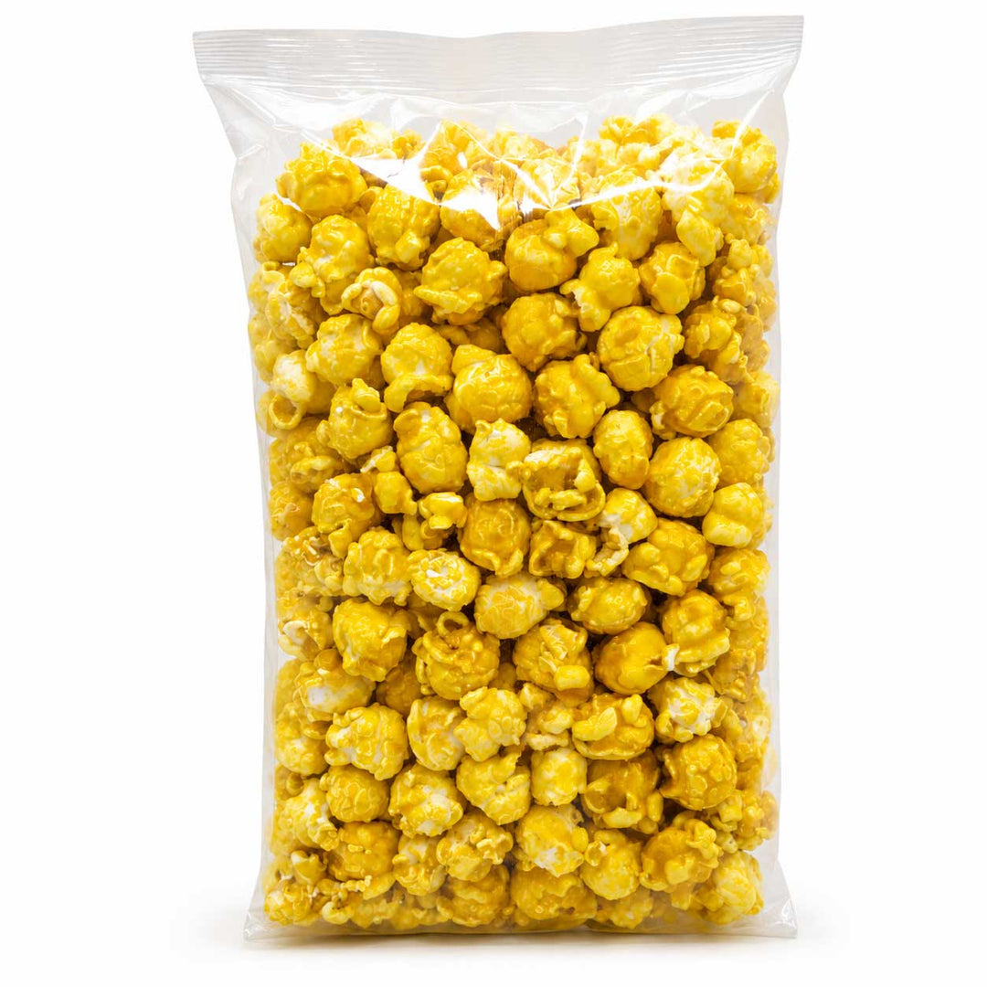 A clear plastic bag filled with bright yellow popcorn on a plain white background.