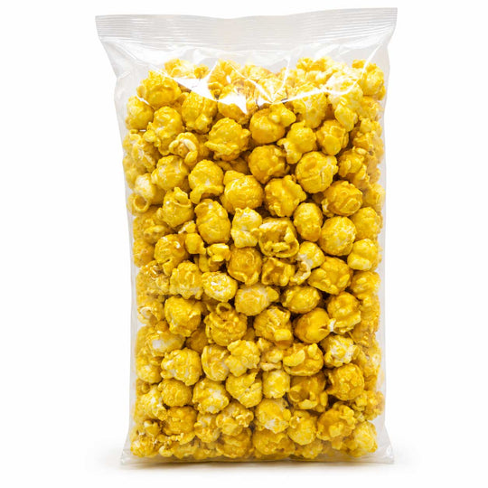 A clear plastic bag filled with bright yellow popcorn on a plain white background.