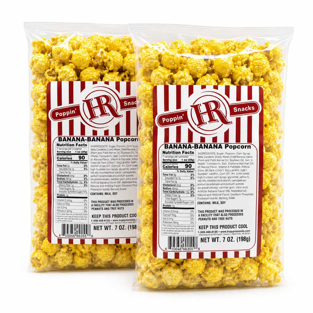 Two 7 oz clear plastic bags of Poppin' Pops Snacks Banana-Banana Popcorn, showing the yellow popcorn inside and a red and white striped label with nutrition facts.