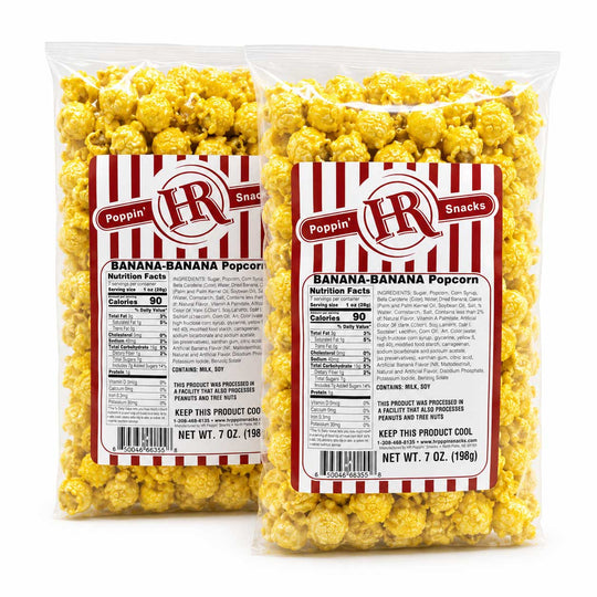 Two 7 oz clear plastic bags of Poppin' Pops Snacks Banana-Banana Popcorn, showing the yellow popcorn inside and a red and white striped label with nutrition facts.